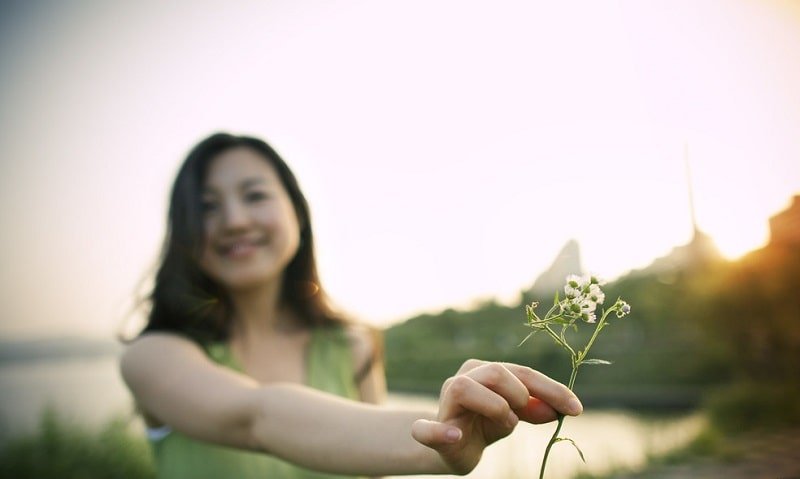 Chica asiatica sosteniendo una flor-min